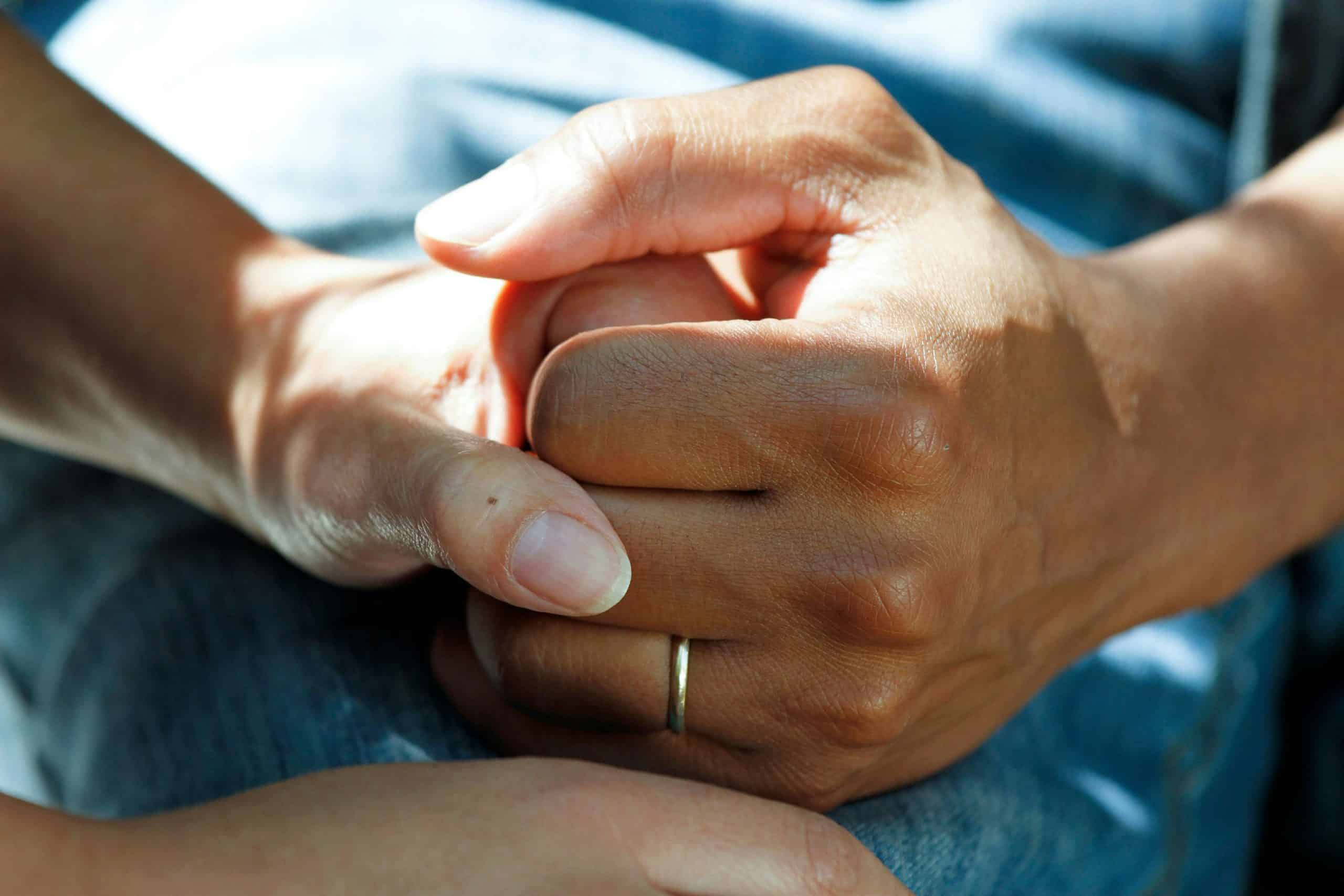 Two hands holding each other tightly for support