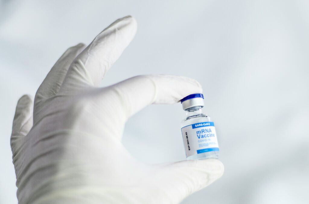 Gloved hand holding mRNA vaccination bottle