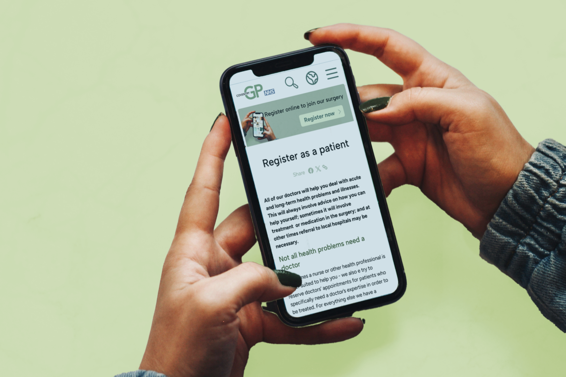 Hands holding a phone with CoventryGP website on it