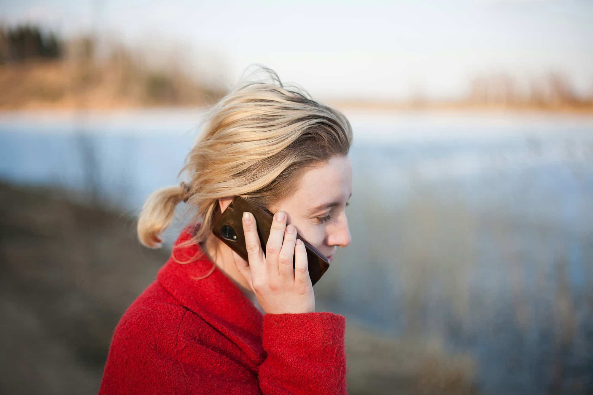 A woman talking on the phone next to a body of water